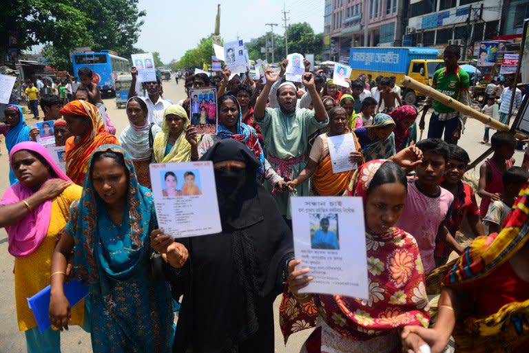 Bangladeshi family members hold up portraits of missing relatives as they march in Savar on the outskirts of Dhaka on May 14, 2013. Bangladesh garment manufacturers said Thursday they would reopen hundreds of factories in a hub outside Dhaka, days after they were shuttered due to unrest over the country's worst industrial tragedy