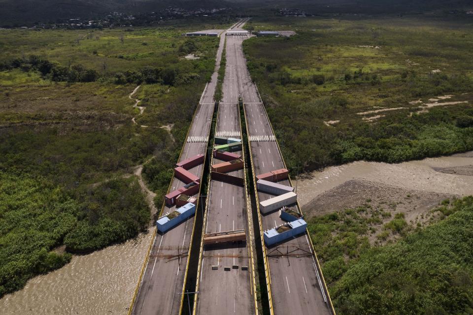 Containers block the Tienditas International Bridge, seen from Cucuta, Colombia, below, which connects with Tienditas, Venezuela, top, as the border has been partially closed for years by the Venezuelan government, Friday, Aug. 5, 2022. The border will gradually reopen after the two nations restore diplomatic ties when Colombia’s new president is sworn-in on Aug. 7, according to announcement in late July by Colombia’s incoming Foreign Minister Alvaro Leyva and Venezuelan Foreign Minister Carlos Faria. (AP Photo/Matias Delacroix)