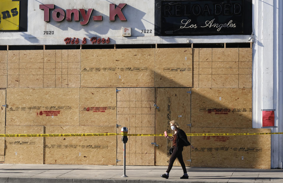 A woman takes photos of a boarded-up store after mass demonstrations looted the area on Saturday night over the death of George Floyd in the Fairfax district of Los Angeles, Monday, June 1, 2020. (AP Photo/Richard Vogel)