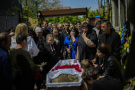 Mourners pay their respects to Volodymyr Losev, 38, during his funeral in Zorya Truda, Odesa region, Ukraine, Monday, May 16, 2022. Volodymyr Losev, a Ukrainian volunteer soldier, was killed May 7 when the military vehicle he was driving ran over a mine in eastern Ukraine. (AP Photo/Francisco Seco)