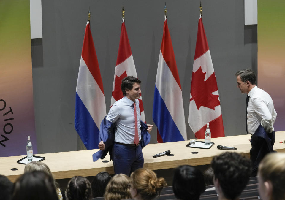 Canada's Prime Minister Justin Trudeau, left, and Dutch caretaker Prime Minister Mark Rutte take off their jackets when meeting with students of the Hague campus of the Leiden University in The Hague, Netherlands, Friday, Oct. 29, 2021. (AP Photo/Peter Dejong)