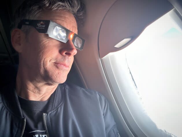 GeekWire reporter Kurt Schlosser tests his eclipse glasses as his flight from Seattle to New York City passes over the Great Lakes. (GeekWire Photo / Kurt Schlosser)