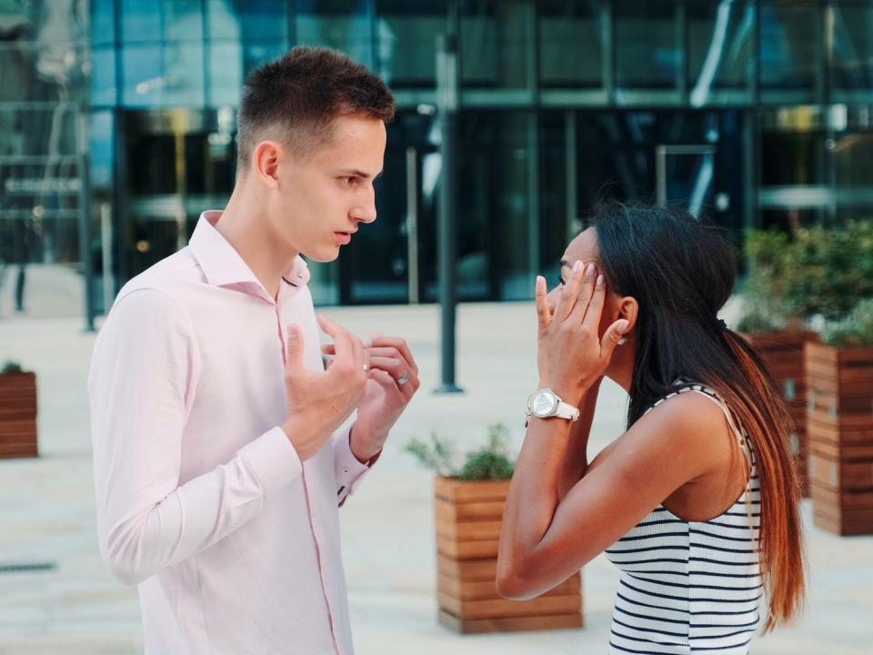 A couple fights in front of a building.