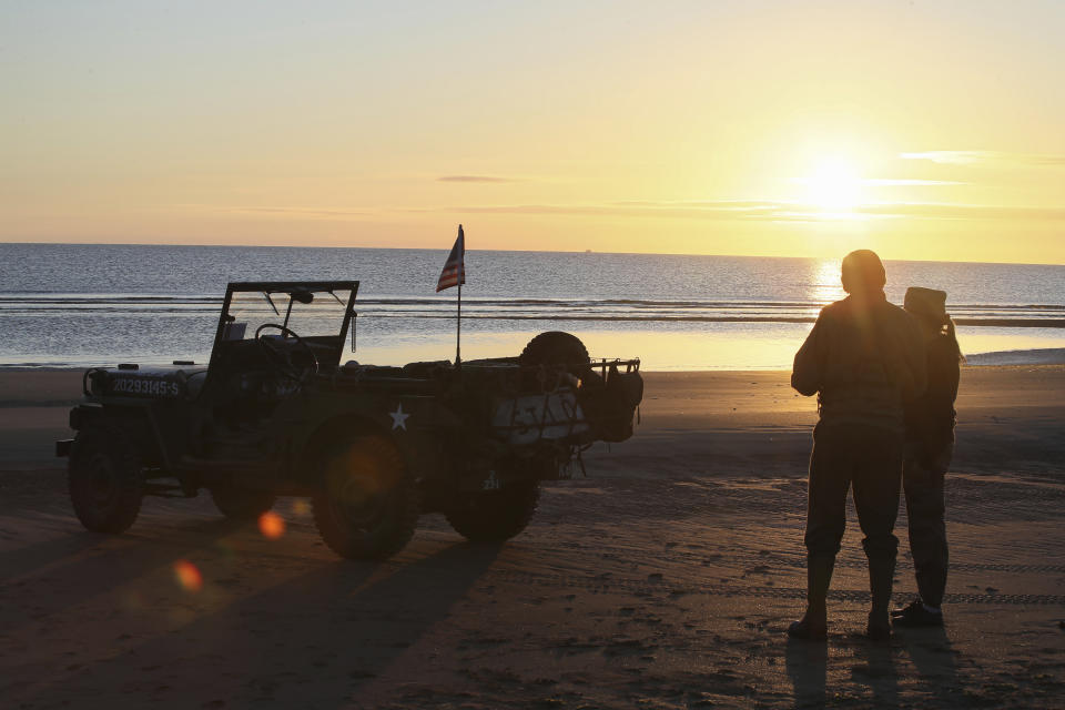 World War II reenactors gather at dawn on Omaha Beach in Saint-Laurent-sur-Mer, Normandy, Sunday, June 6, 2021, the day of 77th anniversary of the assault that helped bring an end to World War II. While France is planning to open up to vaccinated visitors starting next week, that comes too late for the D-Day anniversary. So for the second year in a row, most public commemoration events have been cancelled. (AP Photo/David Vincent)