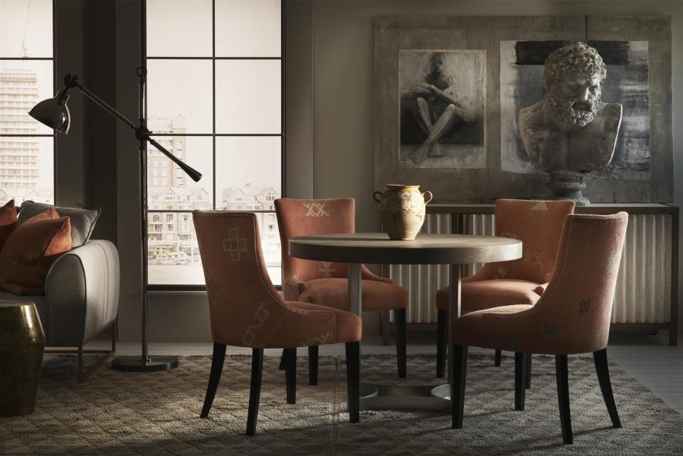 A neutral beige dining room with ancient Greek style sculpture and artwork, with soft orange dining chairs