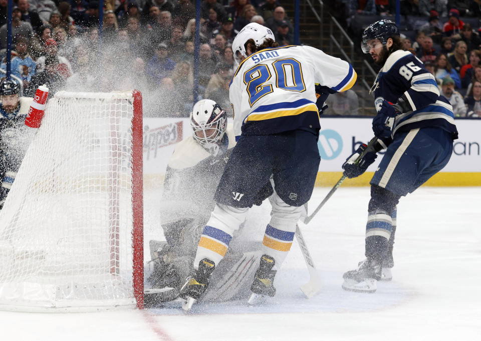 St. Louis Blues forward Brandon Saad, center, works on forcing the puck past Columbus Blue Jackets goalie Michael Hutchinson, left, and forward Kirill Marchenko during the first period of an NHL hockey game in Columbus, Ohio, Saturday, March 11, 2023. Saad scored on the play. (AP Photo/Paul Vernon)
