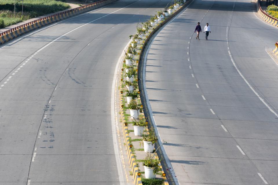 Men walk on a deserted street during a one-day Janata (civil) curfew imposed as a preventive measure against the COVID-19 coronavirus in New Delhi on March 22, 2020. - Nearly one billion people around the world were confined to their homes, as the coronavirus death toll crossed 13,000 and factories were shut in worst-hit Italy after another single-day fatalities record. (Photo by Jewel SAMAD / AFP) (Photo by JEWEL SAMAD/AFP via Getty Images)