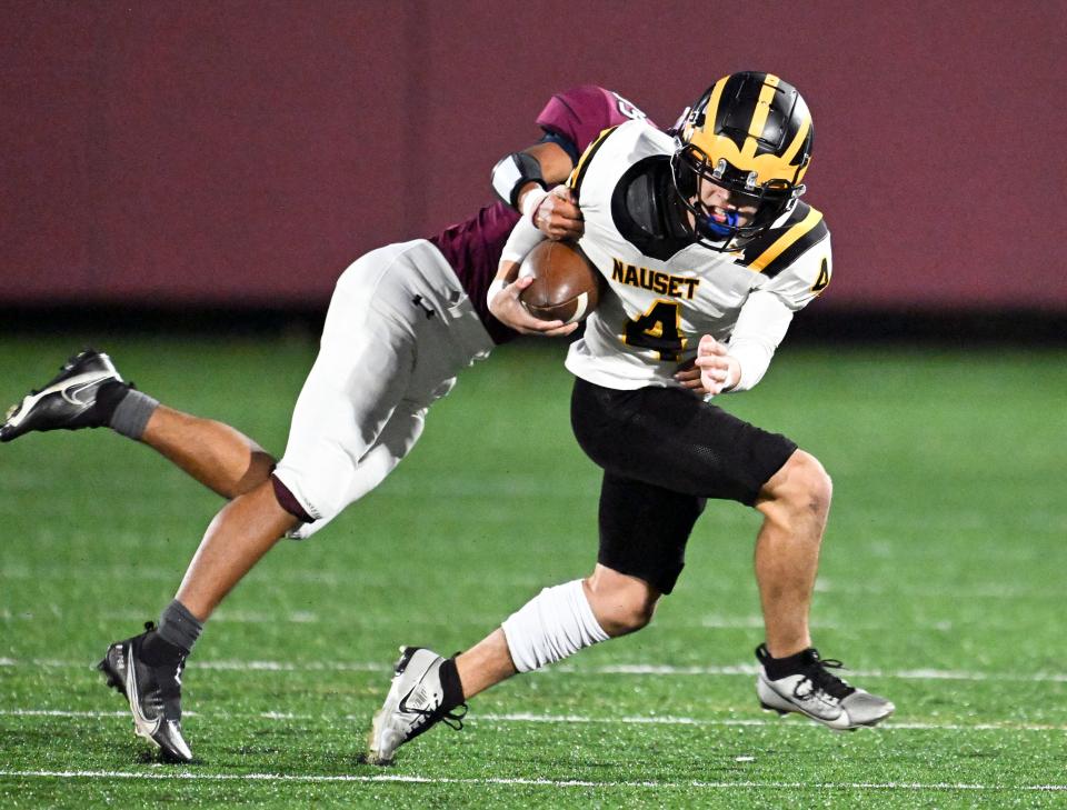 Nauset quarterback Brendan Peno attempts to break the tackle of Jordan Matthews of Falmouth