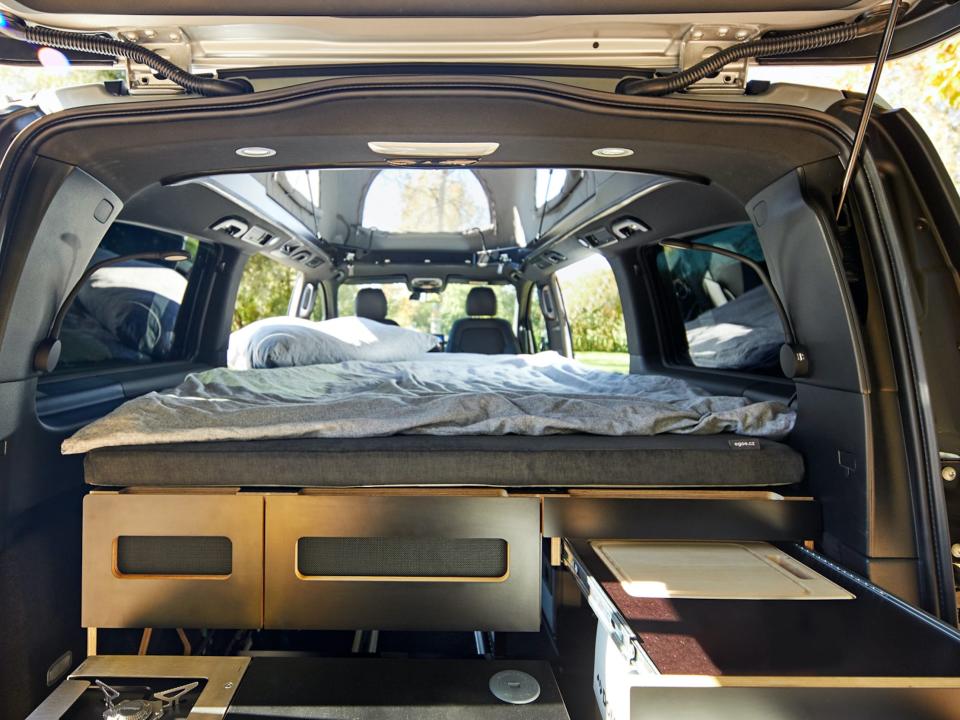 Inside the Mercedes-Benz EQV with cabinets and a bed on top near the pop-top roof of the van.