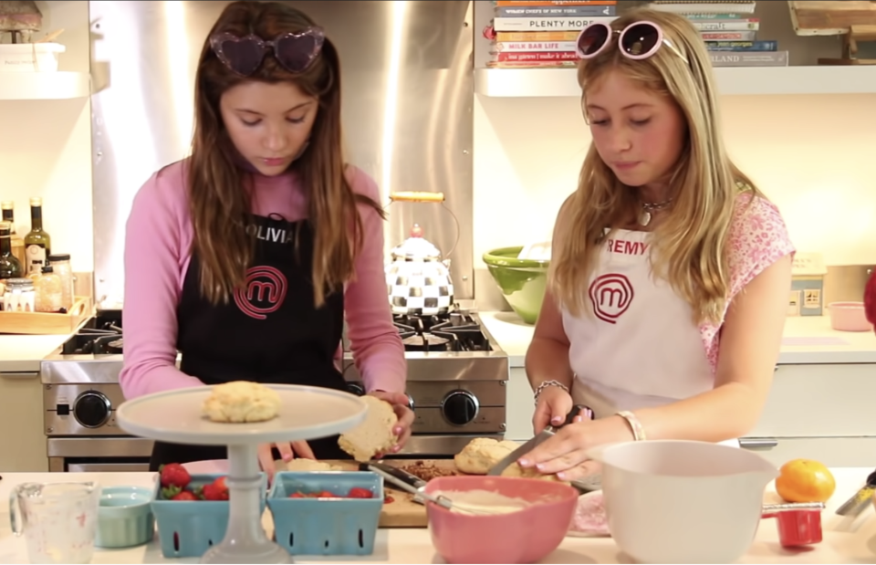 Two girls in brightly colored smocks cook together