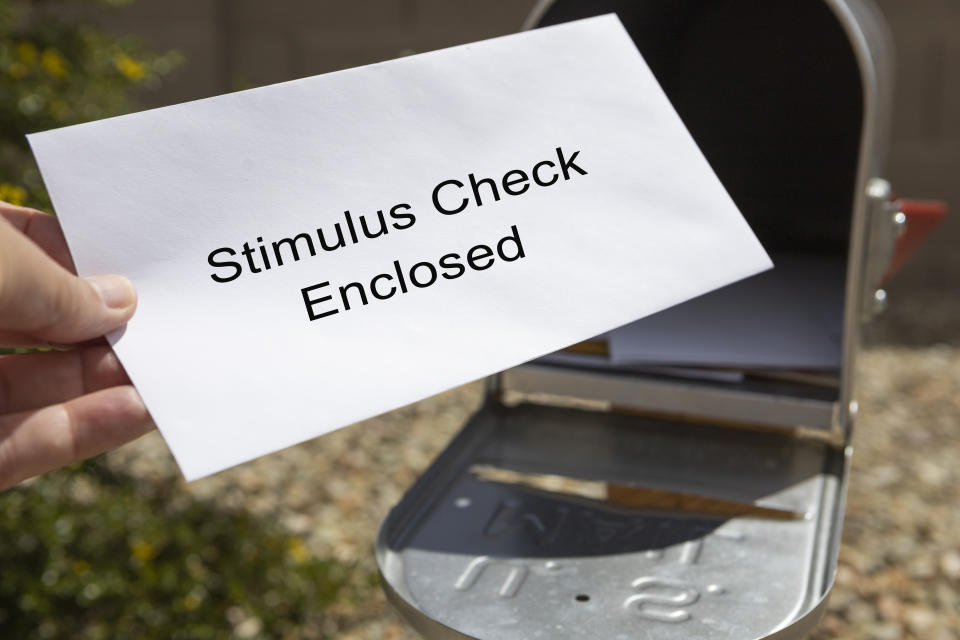 A person retrieves their stimulus check from the mailbox.