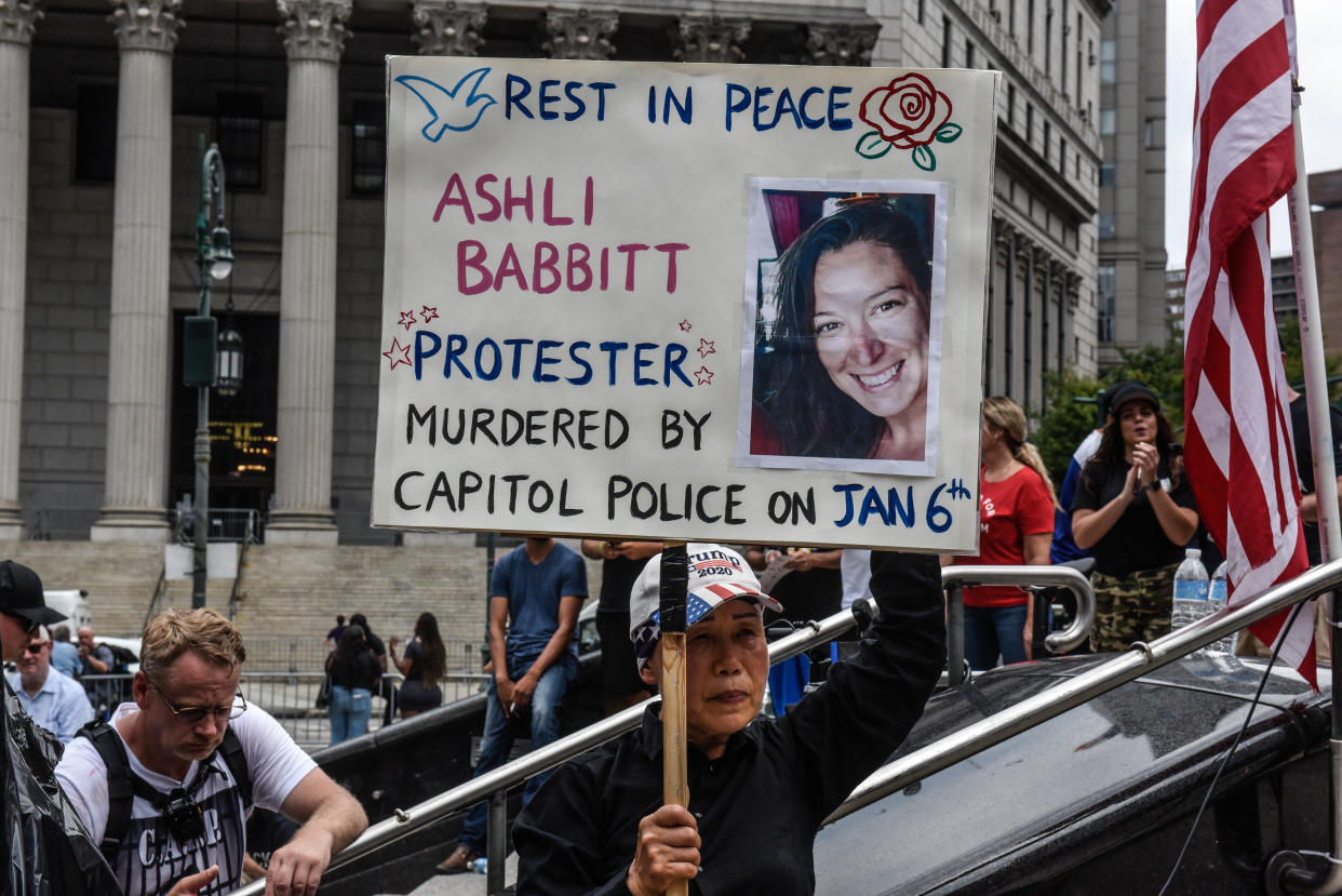 A protester holds a sign about Ashli Babbitt at a rally: Rest in peace, Ashli Babbitt.