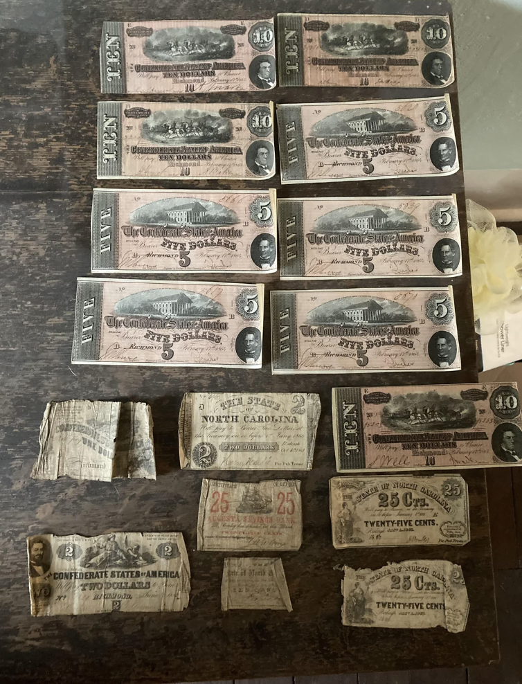 Collection of various old and weathered currency bills, some partial, displayed on a wooden surface