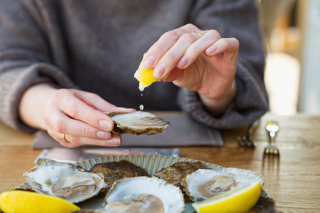 <p>Ilja Enger-Tsizikov / Getty Images</p> Squeezing fresh lemon onto omega-3-rich oysters.