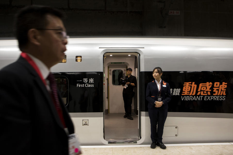 An attendant, right, stands next to an entrance of a Guangzhou-Shenzhen-Hong Kong Express Rail Link (XRL) Vibrant Express train bound for Guangzhou Nan Station in the Mainland Port Area at West Kowloon Station, which houses the terminal for the XRL in Hong Kong, Saturday, Sept. 22, 2018. (Giulia Marchi/Pool Photo via AP)