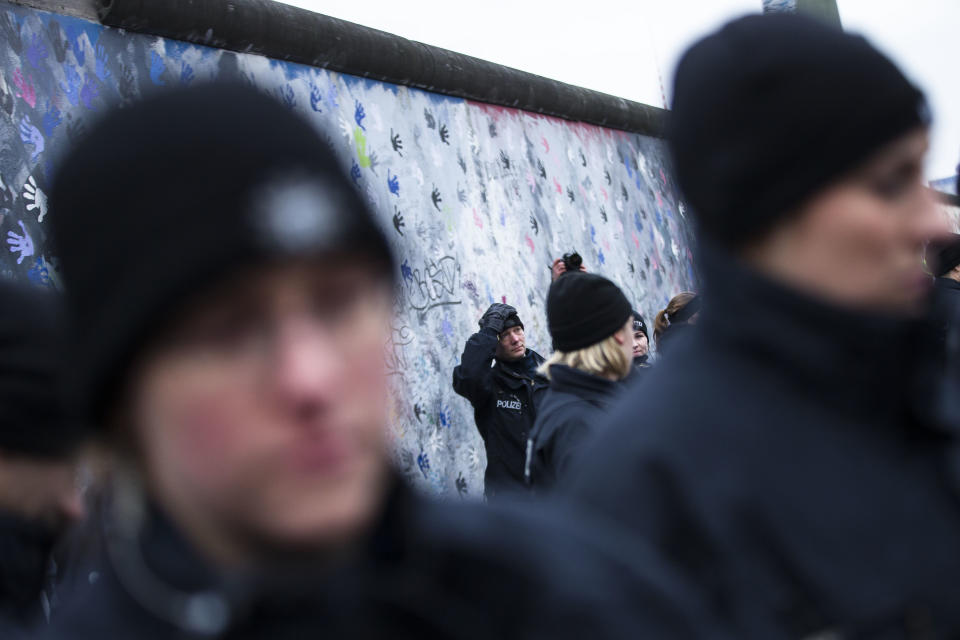 German police officers reacts as they protect a part of the former Berlin Wall in Berlin, Germany, Friday, March 1, 2013. Construction crews stopped work Friday on removing a small section from one of the few remaining stretches of the Berlin Wall to make way for a condo project after hundreds of protesters blocked their path.(AP Photo/Markus Schreiber)