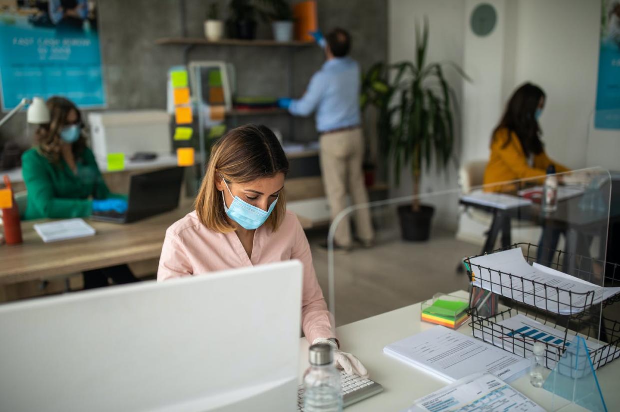 <span class="caption">Maintaining social distancing is a challenge as workplaces reopen during the coronavirus pandemic. </span> <span class="attribution"><a class="link " href="https://www.gettyimages.com/detail/photo/coworkers-with-protective-face-masks-using-computer-royalty-free-image/1227193807?adppopup=true" rel="nofollow noopener" target="_blank" data-ylk="slk:miodrag ignjatovic/E+ via Getty Images;elm:context_link;itc:0;sec:content-canvas">miodrag ignjatovic/E+ via Getty Images</a></span>