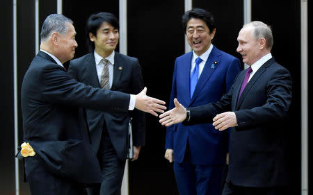 Russian President Vladimir Putin (R) is welcomed by former Japanese Prime Minister Yoshiro Mori (L) beside Japanese Prime Minister Shinzo Abe (2nd R) when he visits the Kodokan Judo Institute, the headquarters of the worldwide judo community, in Tokyo on December 16, 2016. REUTERS/Toru Yamanaka/Pool