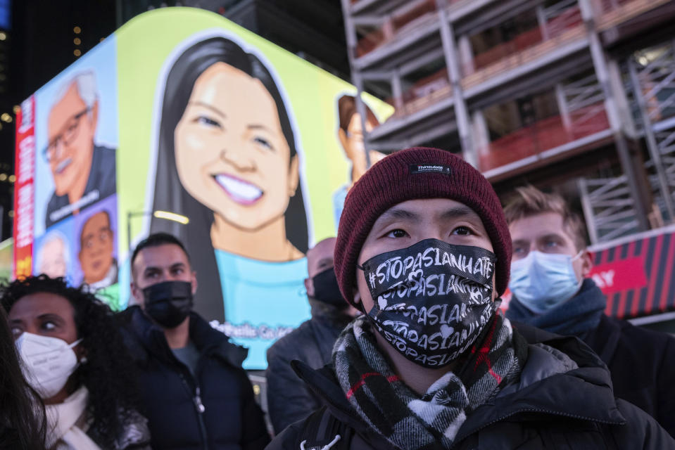 A person wearing a face mask reading, "Stop Asian Hate," attends a candlelight vigil in honor of Michelle Alyssa Go, a victim of a subway attack several days earlier, Tuesday, Jan. 18, 2022, in New York's Times Square. (AP Photo/Yuki Iwamura)