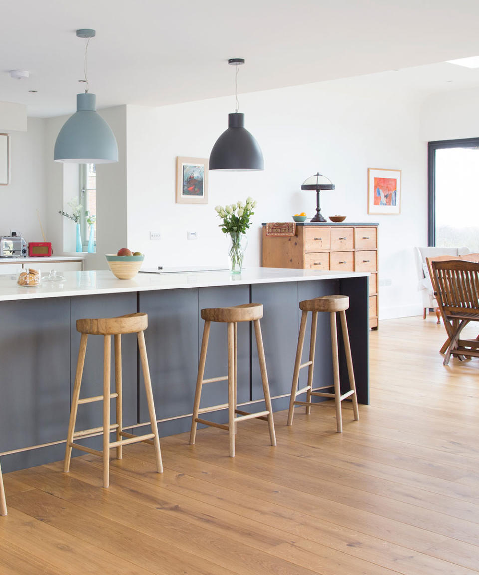 grey kitchen with white counter tops and two lights hanging above counter