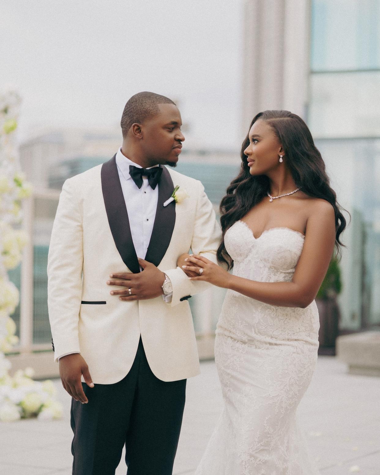 A bride and groom gaze at each other in their wedding attire.