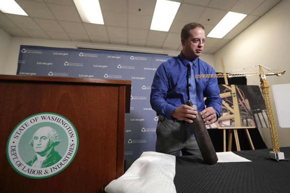 Brian Haight, Crane Program manager for Washington state's Department of Labor and Industries, holds a pin and sleeve of the type used in the collapse of a crane earlier in the year in Seattle that killed four, Thursday, Oct. 17, 2019, in Tukwila, Wash. Washington sState's L&I released the results of its investigation on the collapse Thursday. It found, as experts have long suspected, that the crane toppled because workers who were disassembling it had prematurely removed pins securing the sections of the crane's mast. (AP Photo/Elaine Thompson)