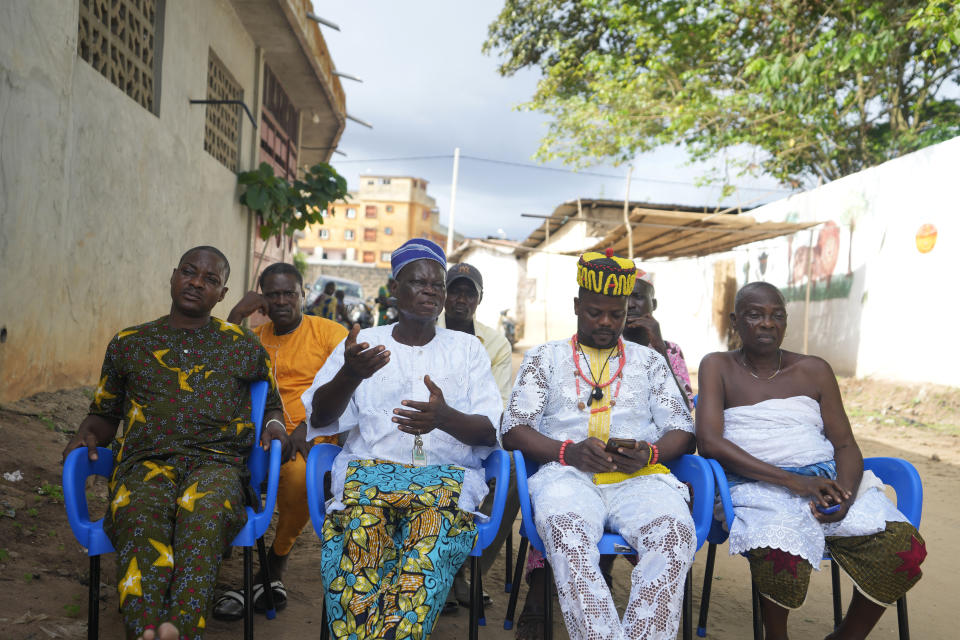 Benoit Sonou, a Voodoo priest, second left, who witnessed the destruction of his forest as a young man, speaks during a meeting outside the only remaining sacred tree of the Odjou Ekoun Oro forest in Houeyogbe, Benin, on Wednesday, Oct. 4, 2023. “When (the government) brought roads to our region and we had to stop everything in the sacred forest, people started getting sick and having all kinds of problems,” Sonou says. (AP Photo/Sunday Alamba)