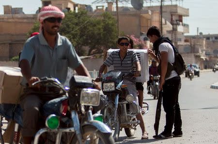 A Kurdish fighter mans a checkpoint at the entrance of the town of Tel Abyad, Raqqa governorate, June 19, 2015. REUTERS/Rodi Said