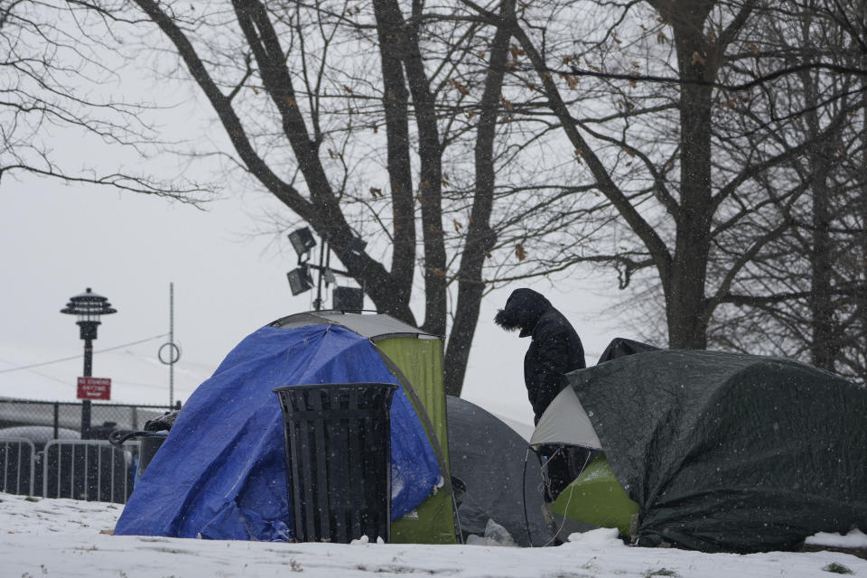 FILE - A man stands near a cluster of small tents pitched near a temporary shelter for migrants on Randall's Island in New York, Friday, Jan. 19, 2024. As New York City struggles to house an influx of immigrants, an unsanctioned tent community is growing outside the gates of the city's largest migrant shelter on Randall’s Island. New immigrants trying to earn a living have also set up a makeshift bazaar to sell coffee, snacks and other items. (AP Photo/Seth Wenig)