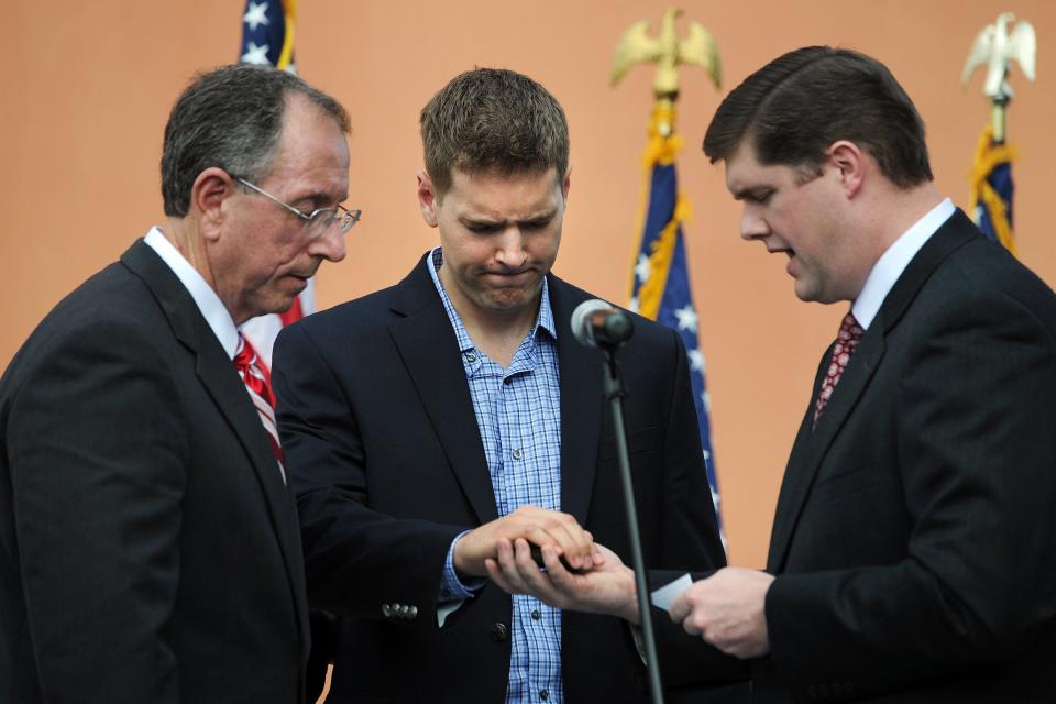 John Snyder (center), son of William Snyder (left), prays intently over the sheriff badge that his father will be wearing as the Rev. Rodney Loper of Hobe Sound Bible Church gives the blessing of the badges during William Snyder's swearing-in ceremony at the Martin County Sheriff's Office in Stuart on Tuesday, Jan. 8, 2013.