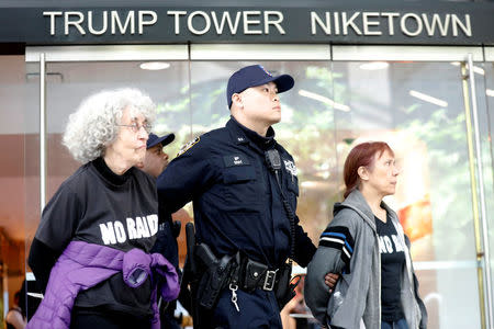 A New York City Police officer (NYPD) escorts protestors after making arrests for demonstrating in Trump Tower in New York, U.S., April 13, 2017. REUTERS/Brendan McDermid