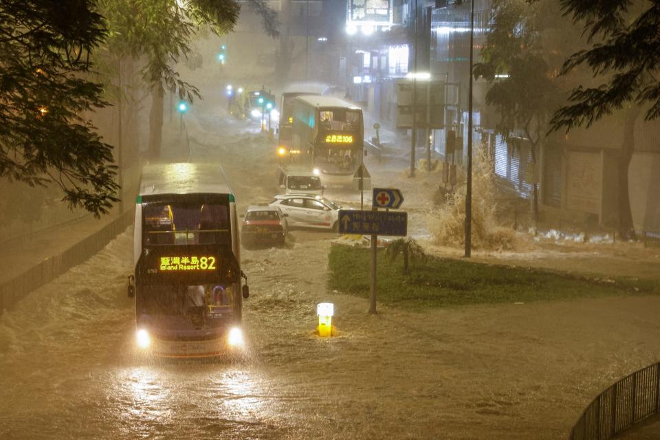 A bus drives past a flooded area during heavy rain, in Hong Kong.