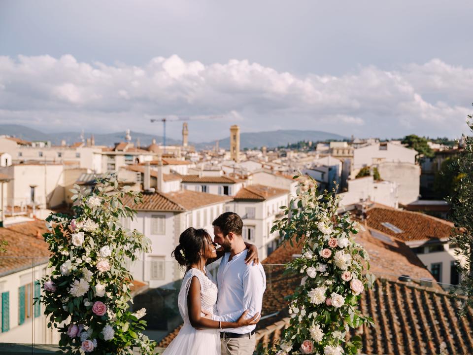 a wedding ceremony on the roof of a building in florence italy with a bride and groom smiling at each other