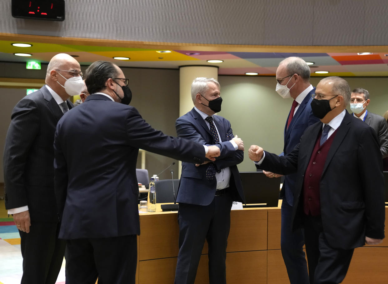 Austrian Foreign Minister Alexander Schallenberg, second left, greets Cypriot Foreign Minister Ioannis Kasoulides, right, during a meeting of EU foreign ministers at the European Council building in Brussels, Monday, Jan. 24, 2022. European Union foreign ministers are aiming Monday to show a fresh display of resolve and unity in support of Ukraine, amid deep uncertainty about whether President Vladimir Putin intends to attack Russia's neighbor or send his troops across the border. (AP Photo/Virginia Mayo)