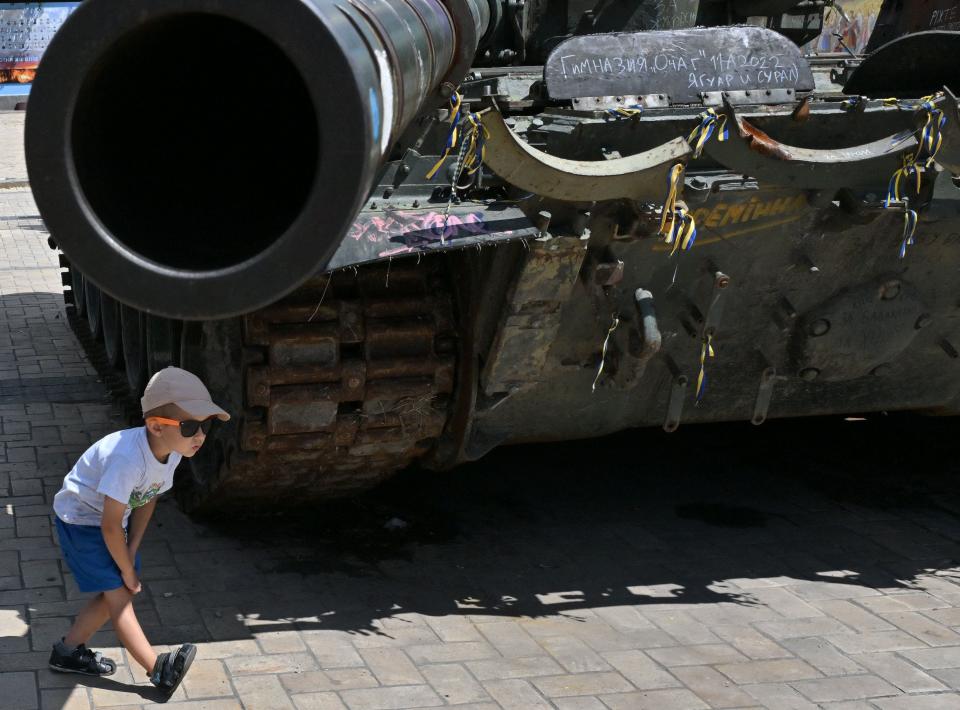 A boy walks underneath the barrel of a tank during an open-air exhibition of destroyed Russian military vehicles at Mykhaylo Square in Kyiv, on Thursday.