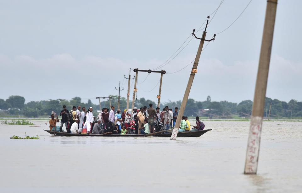 Indian villagers travel by boat through floodwaters on July 4, 2017.