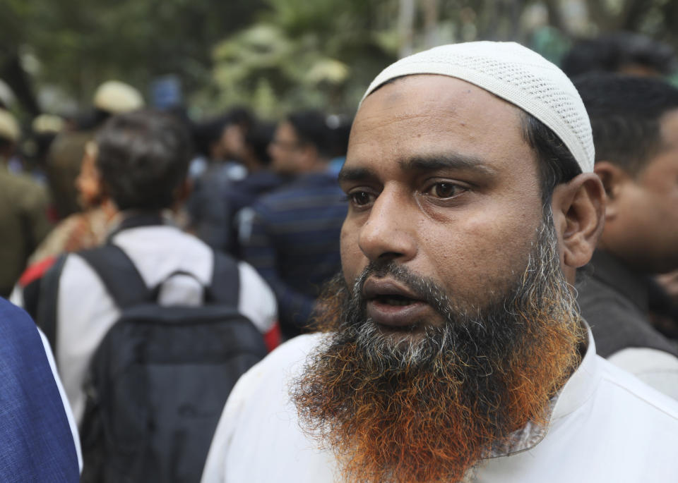 Mohammad Naushad, who is reported to saved the life of at least 10 people, wait outside mortuary with his relatives and friends, in New Delhi, India, Sunday, Dec. 8, 2019. Dozens of people died on Sunday in a devastating fire at a building in a crowded grains market area in central New Delhi, police said. (AP Photo/Manish Swarup)