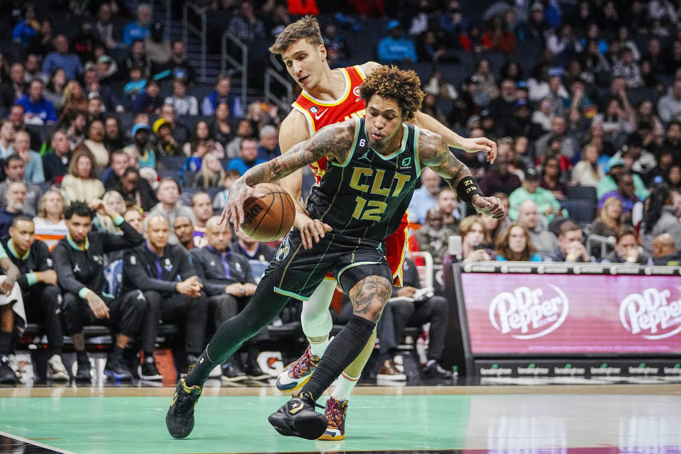 Charlotte Hornets guard Kelly Oubre Jr., front, drives past Atlanta Hawks guard Bogdan Bogdanovic, rear, during the first half of an NBA basketball game Friday, Dec. 16, 2022, in Charlotte, N.C. (AP Photo/Rusty Jones)