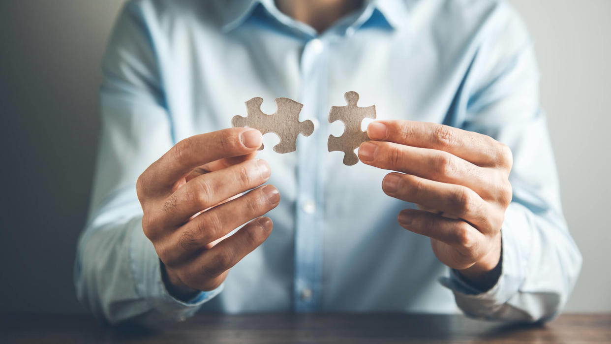 man hand holding two puzzle.