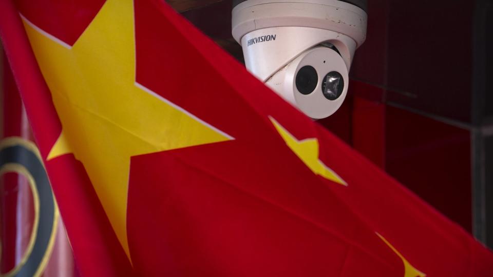 Eine chinesische Flagge weht neben einer Sicherheitskamera der Firma Hikvision in Peking.