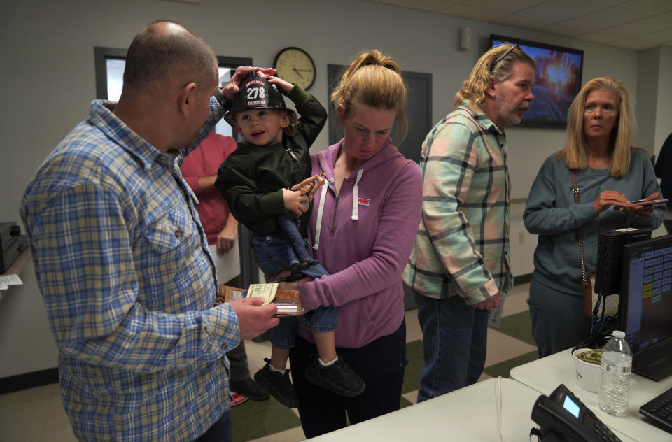 Jason Spade, left, puts a plastic fireman's hat on his son Patrick, while he and his wife Lindsay order from the Swissvale Fire Department fish fry in Pittsburgh, on Friday, Feb. 24, 2023. Fish fries have been a longtime Catholic tradition in Western Pennsylvania but increased in popularity in 1966 after the Second Vatican Council announced that not eating meat on Fridays was optional, except during Lent. Today they are held anywhere, from churches to fire stations to restaurants. (AP Photo/Jessie Wardarski)