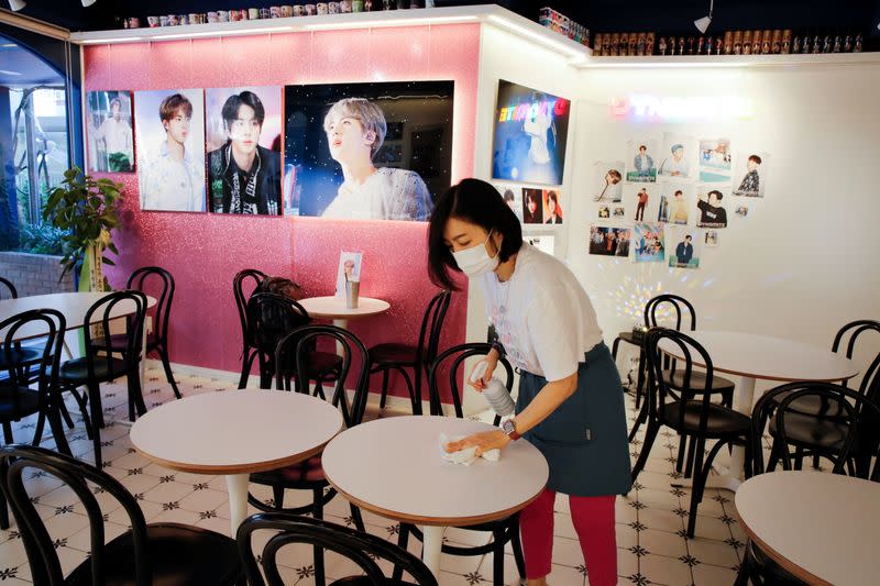 Cafe owner Kim Eun-hee, fan of K-pop boy band BTS, cleans desks with disinfectant in her cafe in Seoul