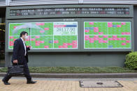 A man walks by an electronic stock board of a securities firm in Tokyo, Wednesday, May 19, 2021. Asian shares fell Wednesday, tracking a decline on Wall Street led by big technology stocks. (AP Photo/Koji Sasahara)