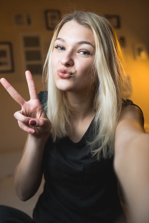 a girl taking a selfie with a peace sign and duck face