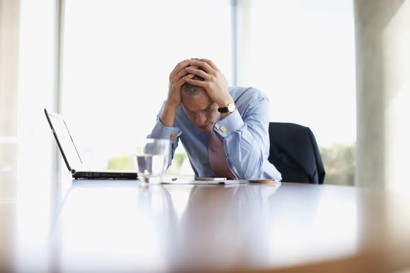 Businessman with hands over head looking worried.