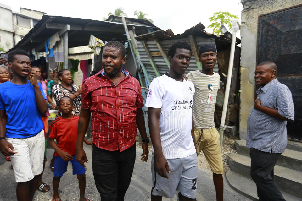 In this May 24, 2019 photo, Barbecue, whose real name is Jimmy Cherizier, center left, walks as residents chant "Barbecue for life" in his neighborhood in Lower Delmas, a district of Port-au-Prince, Haiti. He’s a former policeman, a suspect in the massacre of dozens of men, women and children and a hero in his neighborhood, followed by crowds of adoring residents who consider him their protector. (AP Photo/Dieu Nalio Chery)