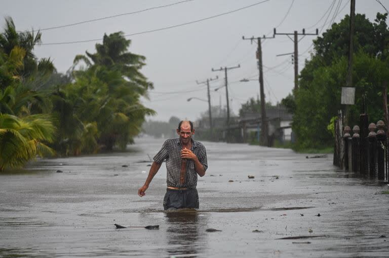 Residentes de la ciudad costera de Guanimar en la provincia de Artemisa, al suroeste de La Habana, caminan por una calle inundada después del paso del huracán Helene el 25 de septiembre de 2024.