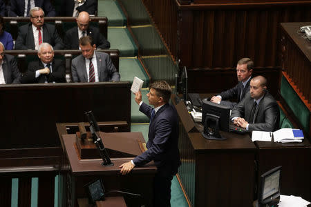 Leader of Modern party (.Nowoczesna) Ryszard Petru presents a copy of Timothy Snyder's "On Tyranny" as leader of Law and Justice (PiS) party Jaroslaw Kaczynski gestures during a debate before the voting on the bill that calls for an overhaul of the Supreme Court, at the parliament in Warsaw, Poland, July 20, 2017. Agencja Gazeta/Slawomir Kaminski/via REUTERS