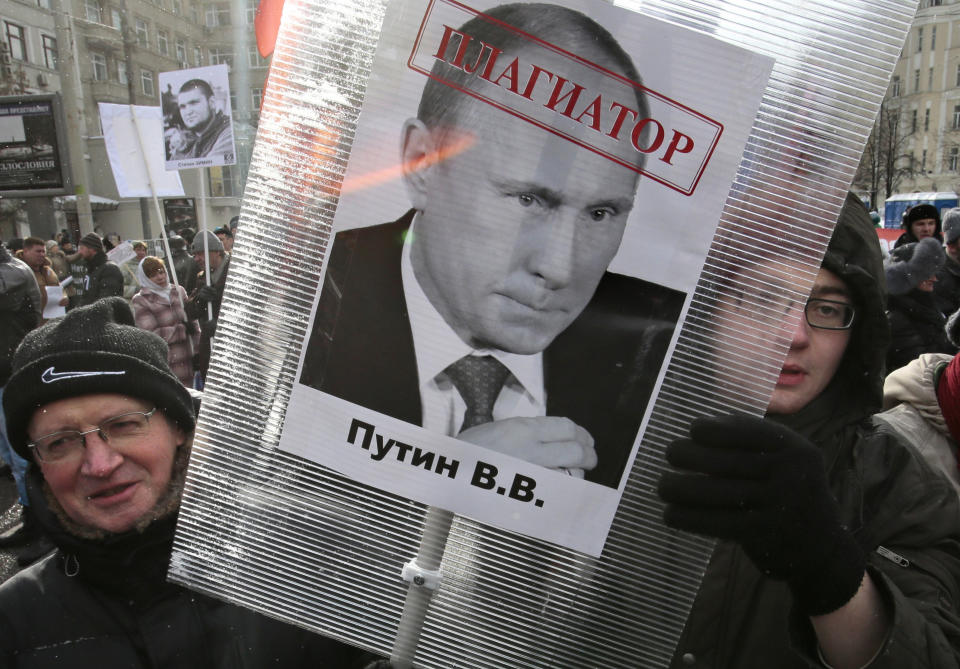 FILE - In this March 2, 2013 file photo, opposition activists hold a poster with a portrait of Russian President Vladimir Putin that says "Plagiarist," during a protest in Moscow. Civil rights and liberties around the world declined for the eighth straight year, dragged down by the Egyptian military's coup, Venezuela clinging to authoritarianism and Russia's crackdown on opposition groups, according to a pro-democracy watchdog group. (AP Photo/Mikhail Metzel, File)