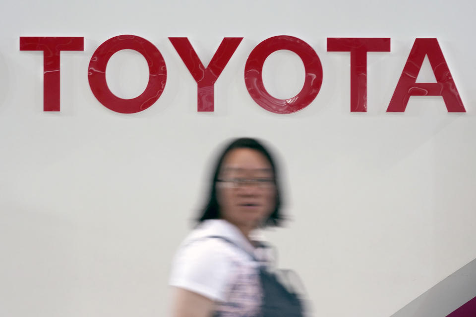 A visitor walks by the logo of Toyota at a show room in Tokyo Friday, Aug. 2, 2019. Toyota has reported a nearly 4% increase in fiscal first quarter profit on improved sales, but the Japanese automaker slightly lowered its full year forecasts because of unfavorable currency exchange rates. (AP Photo/Eugene Hoshiko)
